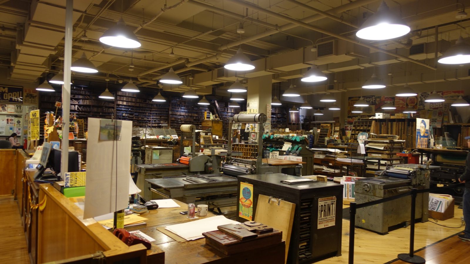 Working letterpress shop floor with proof press and wall of type cases